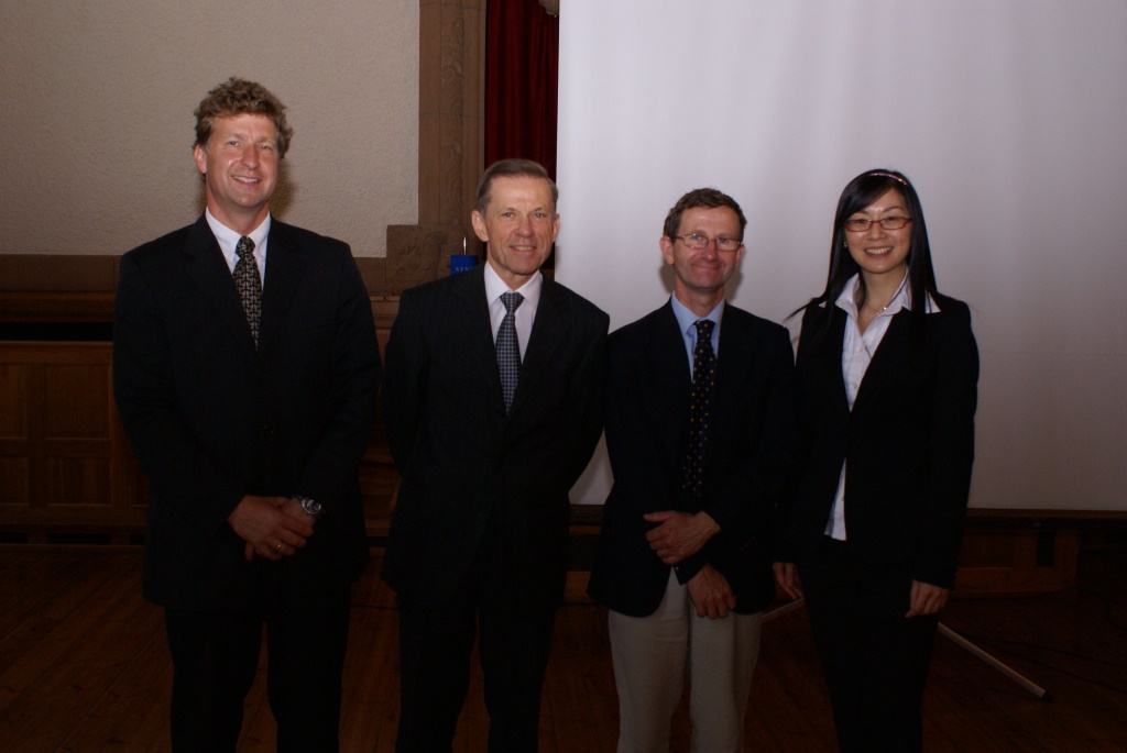 Professors and student standing in front of a projector screen. Photo.