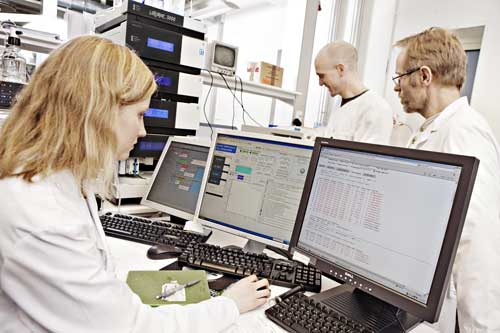 View in the PROMEC laboratory. One researcher analyses data in a computer while 2 others inspect the instrumentation in the background.