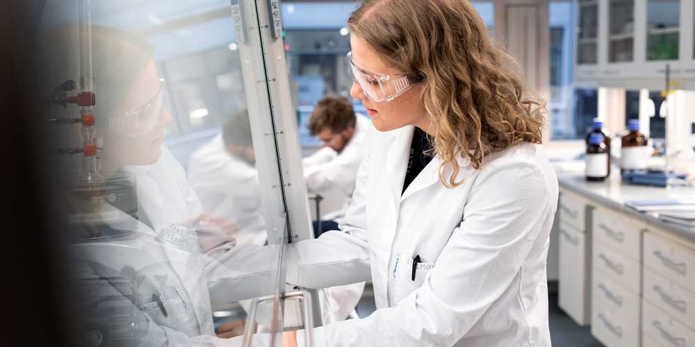 A female students looks into a chemistry fume cupboard. Photo 