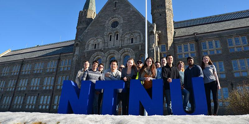 Students are standing behind NTNU letters
