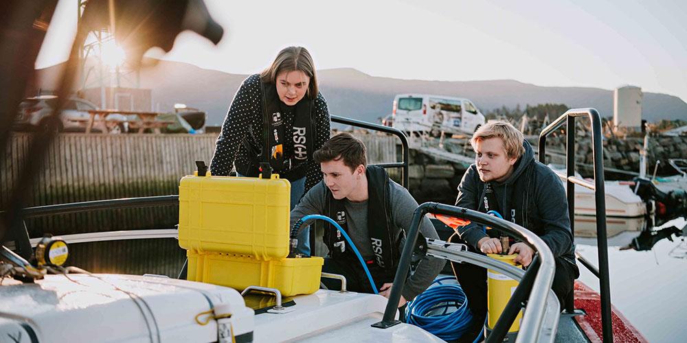 Students looking at the results from tests they have carried out in the fjord. Photo: Tone Molnes.