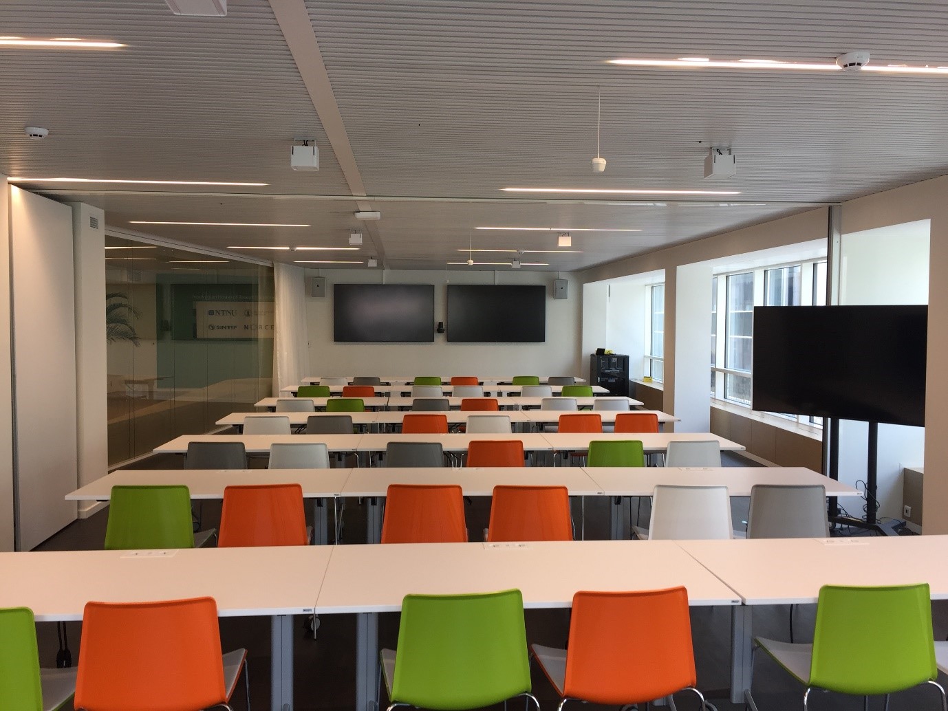 Full meeting room in seminar set-up with twenty-four tables and forty-eight chairs. Foto.