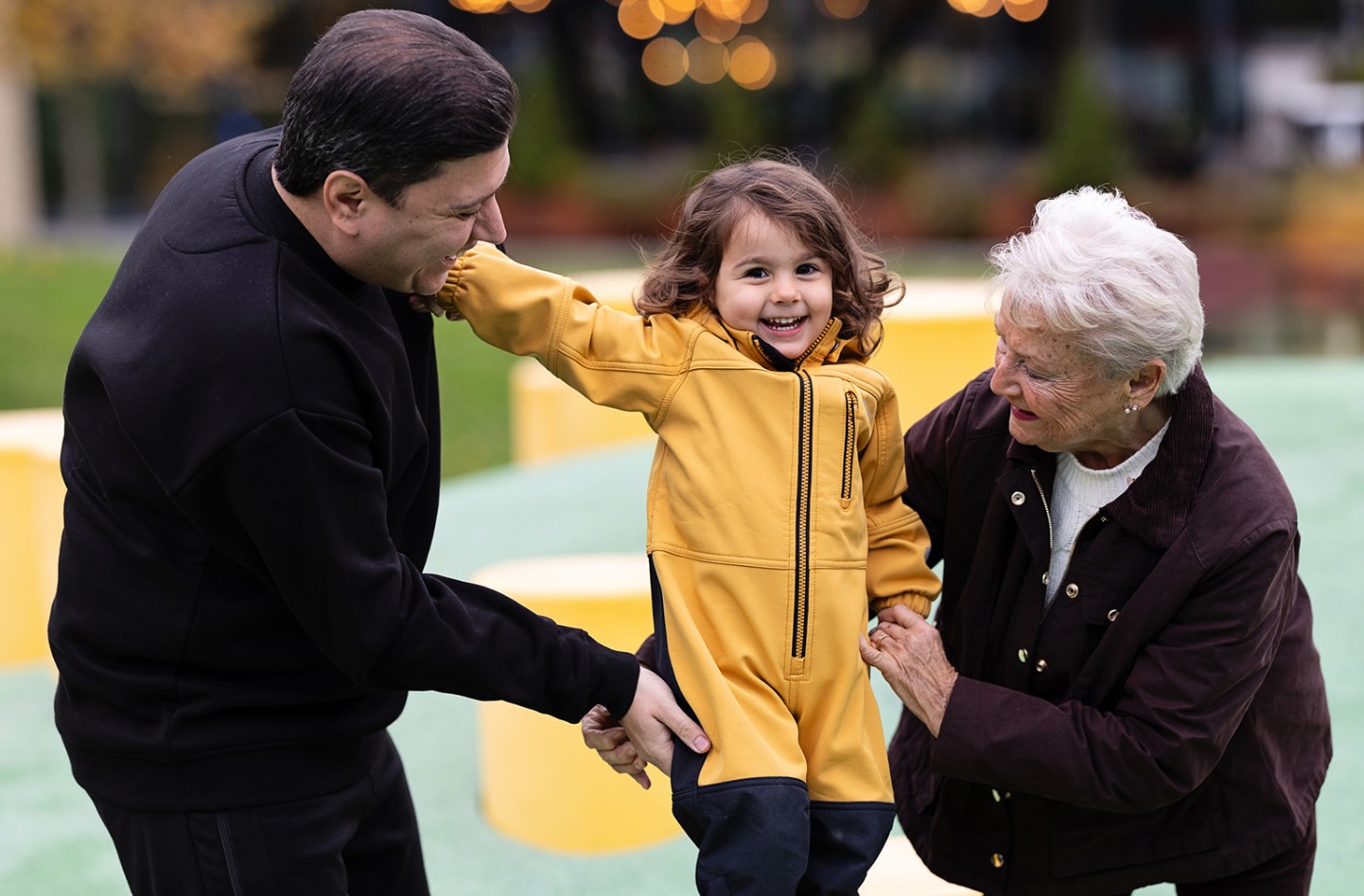 Three generations playing outdoors. Father, girl, grandmother.