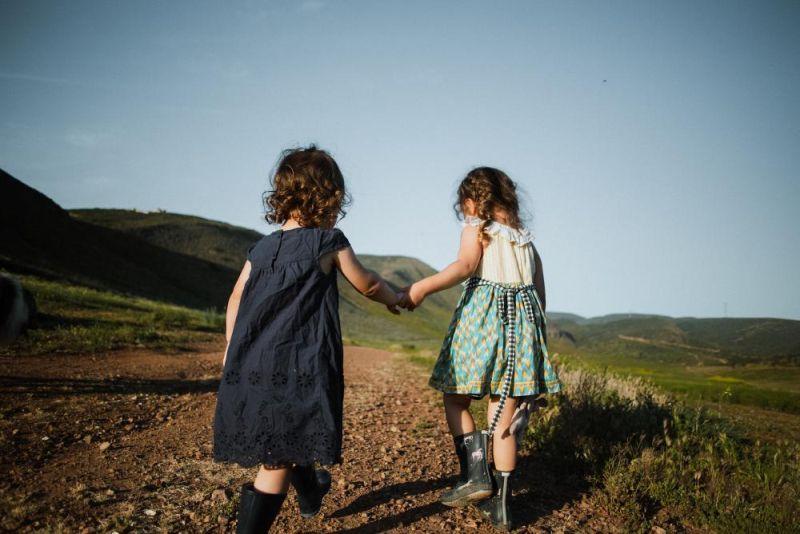 Girls holding hands running away from the photographer. Photo
