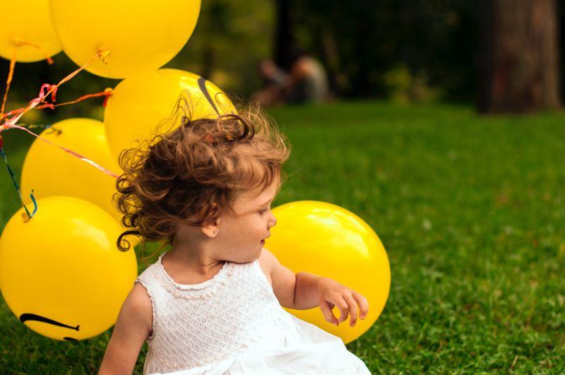 Girl playing with yellow balloons. Photo