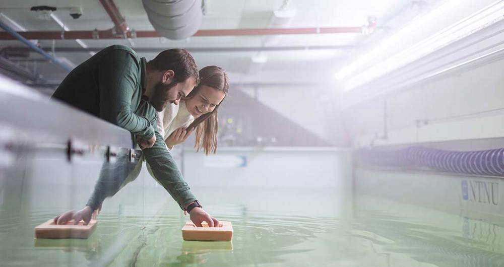Students floating model boats in indoor basin