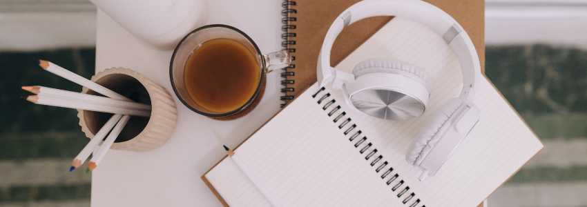Office desk with pencils, coffee, notebooks and headphones. Photo