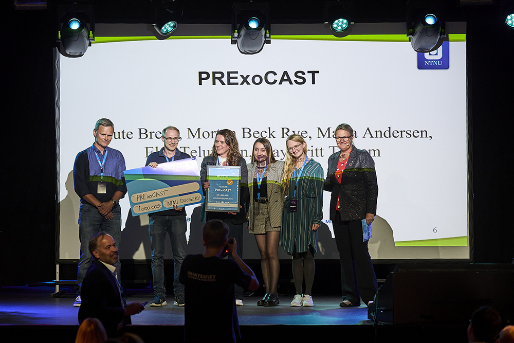 Innovators receive financial support. They stand on a podium and show off a large check.