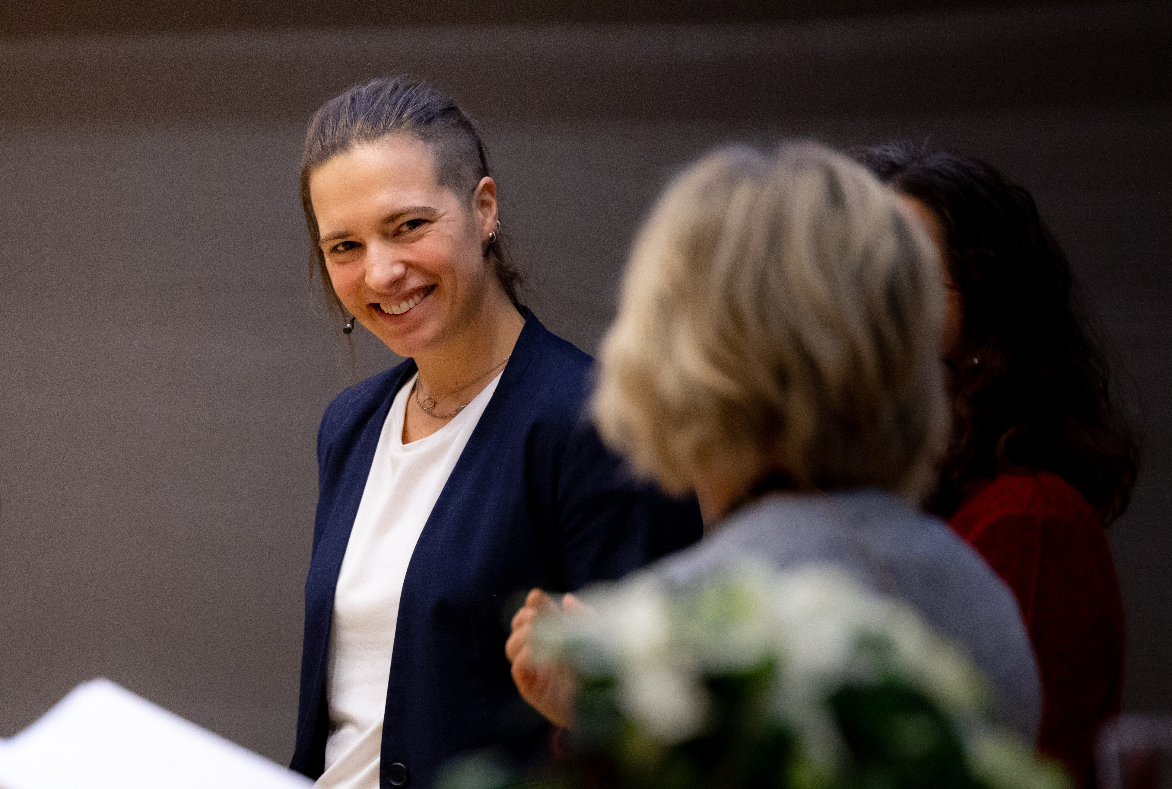A portrait of Inga Strümke, smiling, looking at a woman standing in front of the camera