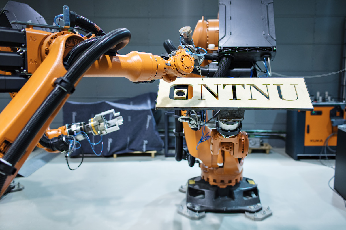 Robot writing ntnu on a wooden board