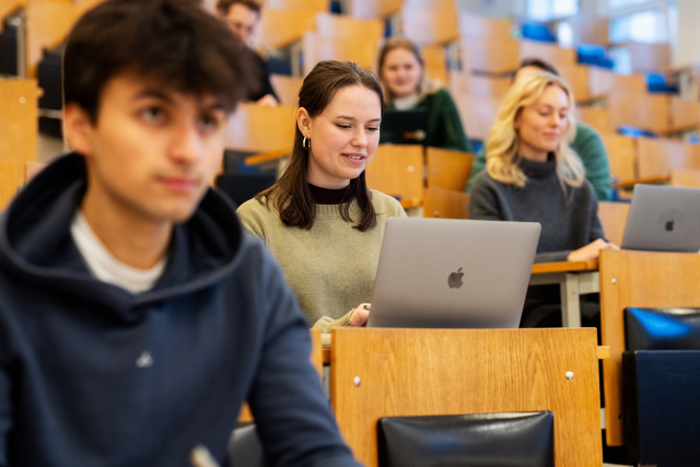 Several students sitting in a lecture-room. 
