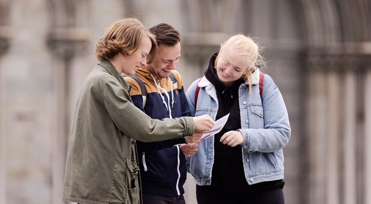 Three students studying a piece of paper. Photo