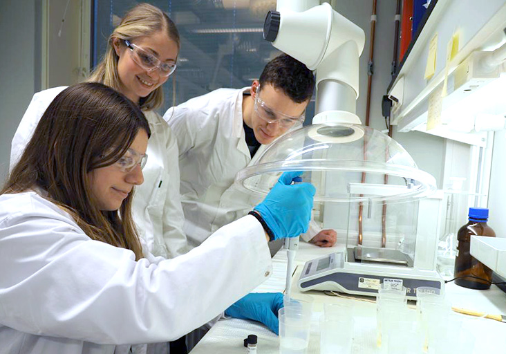 Three researchers with an experiment in the lab. Photo