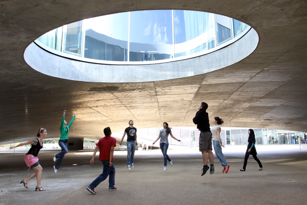 Students jumping up towards an opening in the roof