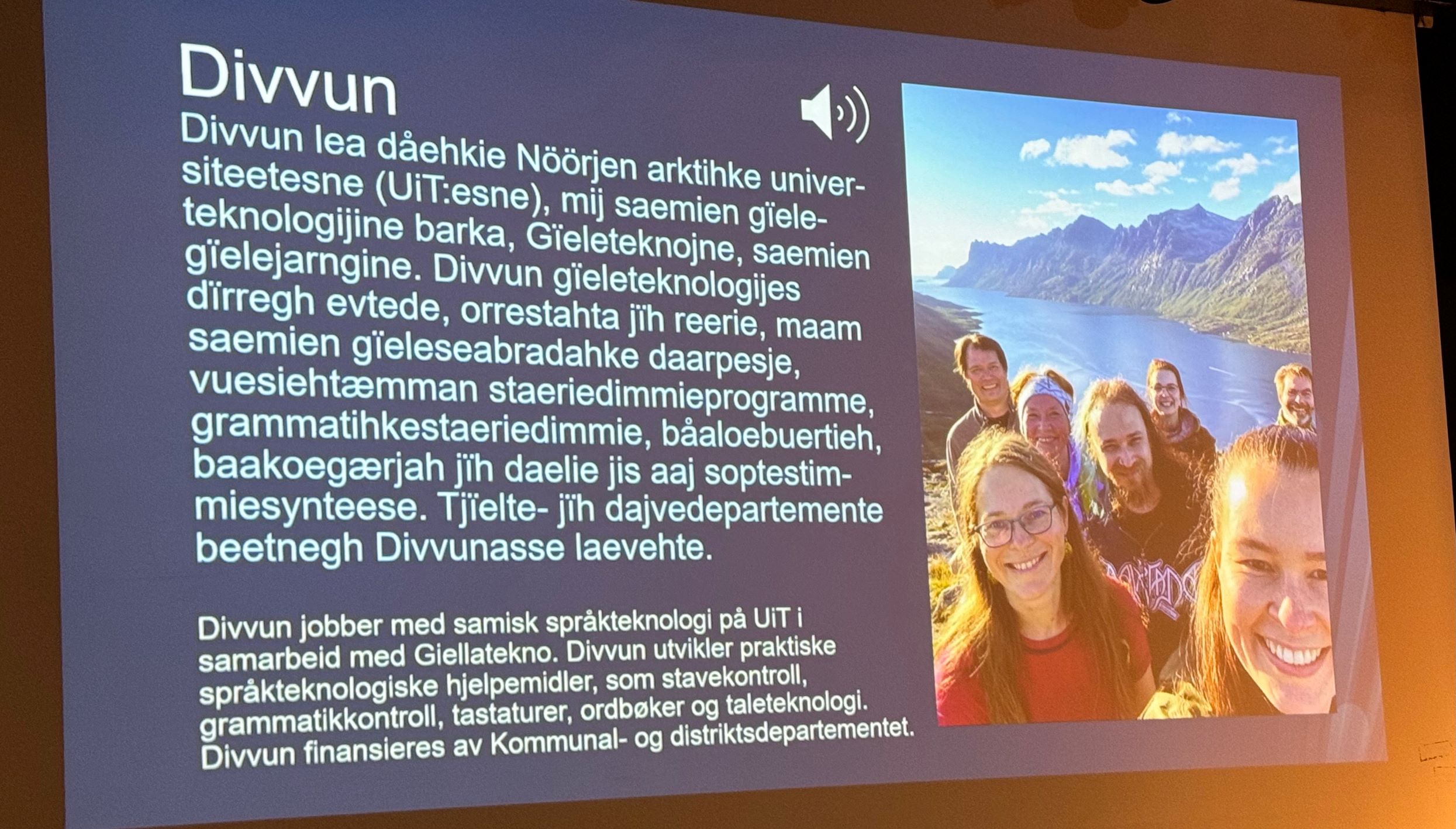 A picture of a presentation slide with tekst in sami and a picture of smiling people