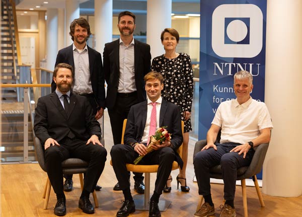 Photo of the PhD candidate in centre with the main supervisor to the left and head of department to the right, and the 3 members of the assessment committee standing behind.
