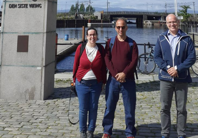 Three people standing outside in the sun. Photo