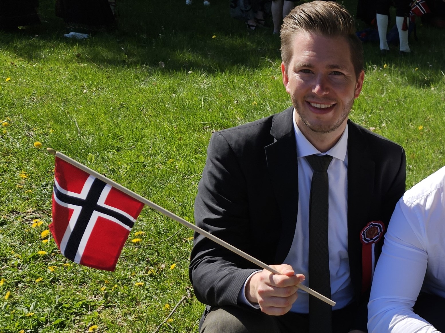 Person smiling and holding the norwegian flag. Photo