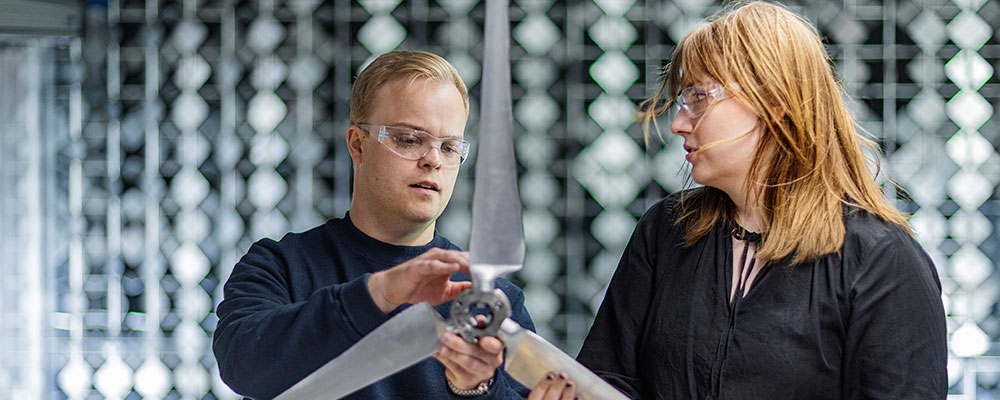 Two people holding a small wind turbine