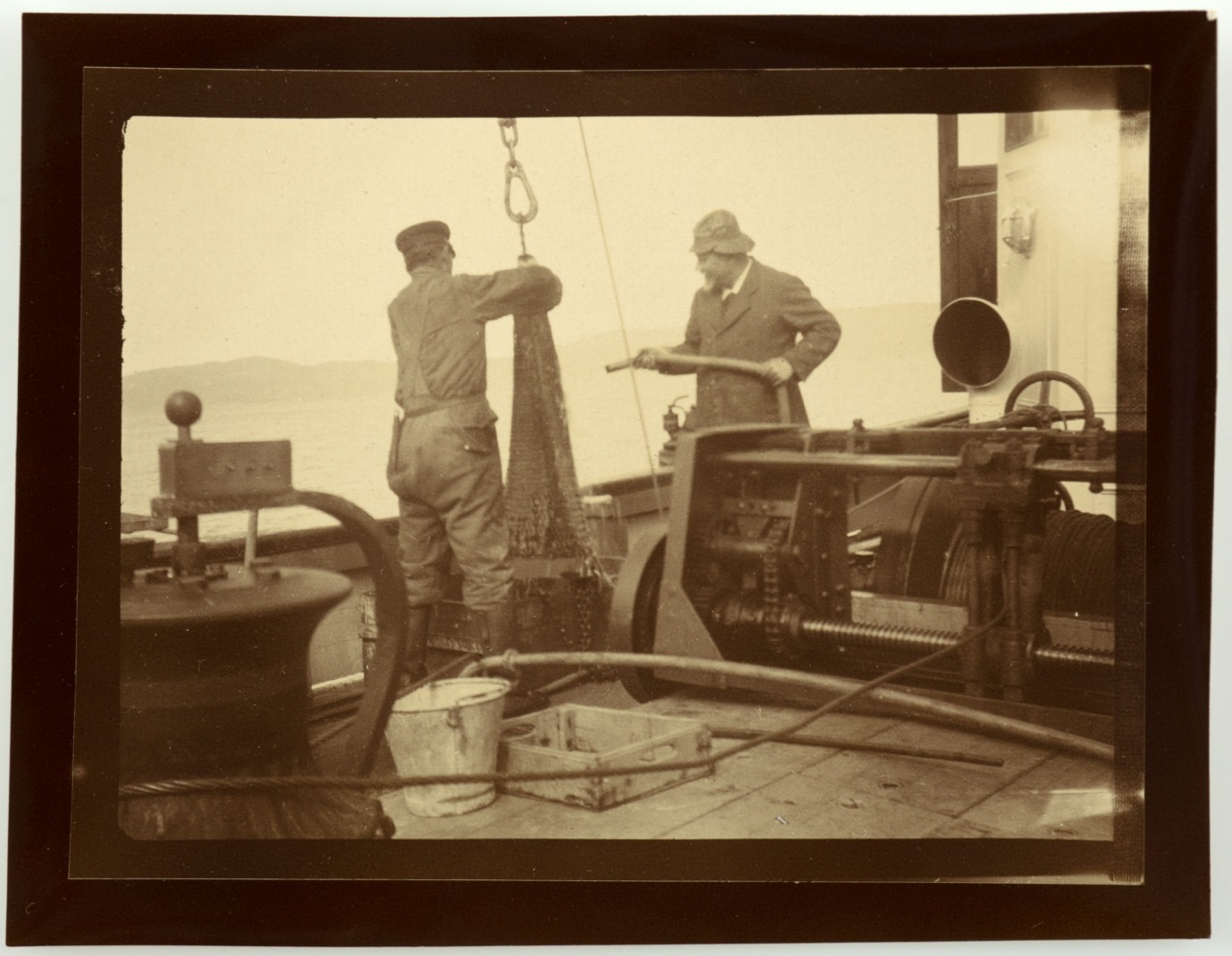 Old photo (1922) of two men working on the deck of a boat