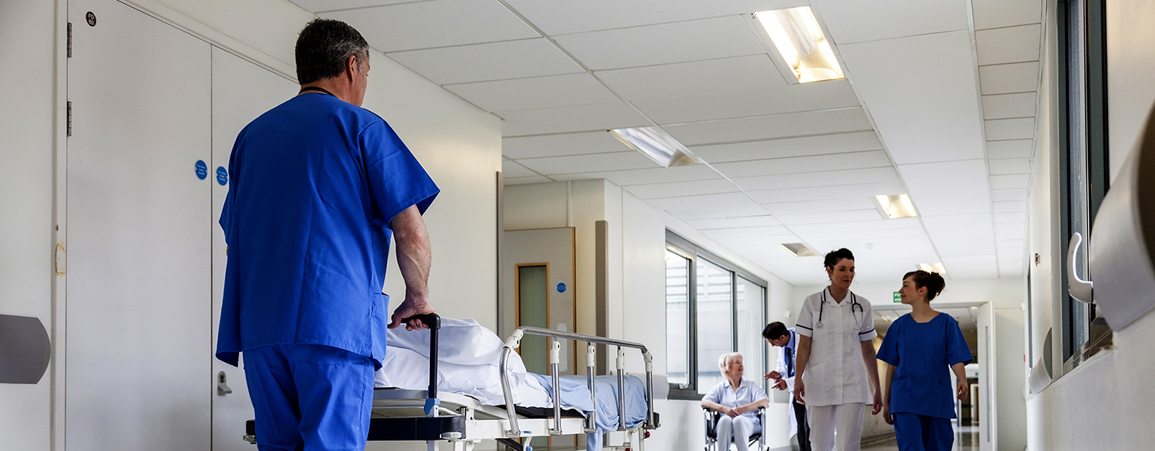Hospital employee rolling a bed. Photo: Shutterstock