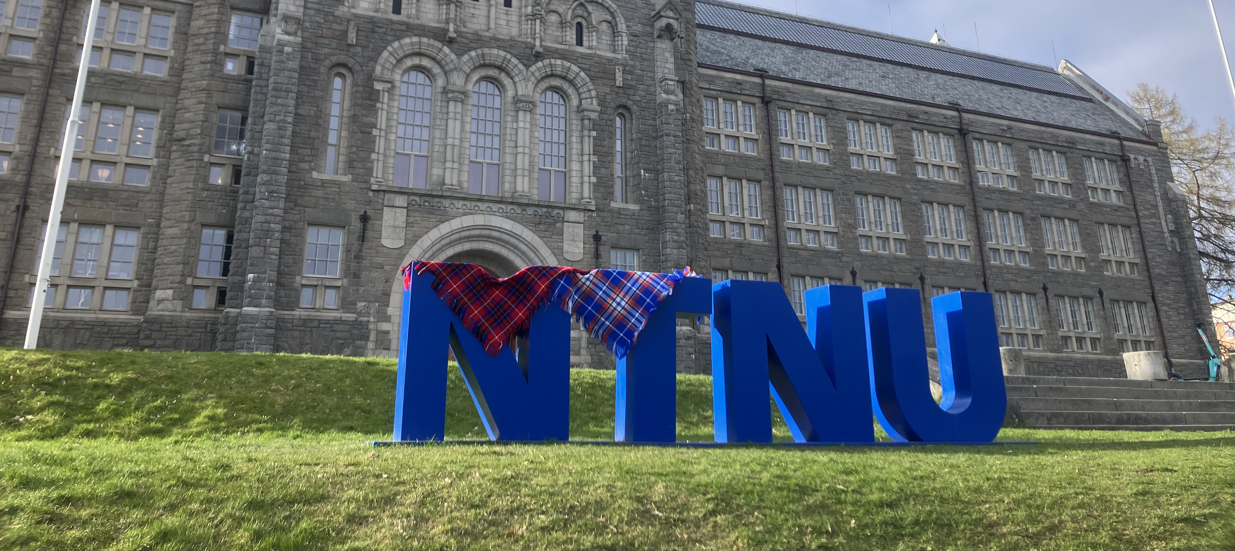 The NTNU letters in front of the main building, with two Sami shawls draped over the letters. Photo.