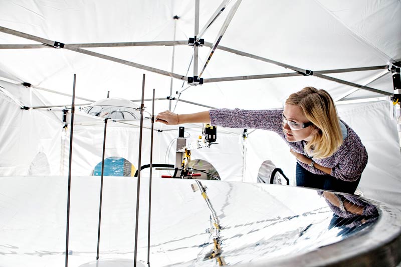 Students adjusting model of a solar cell in a tent