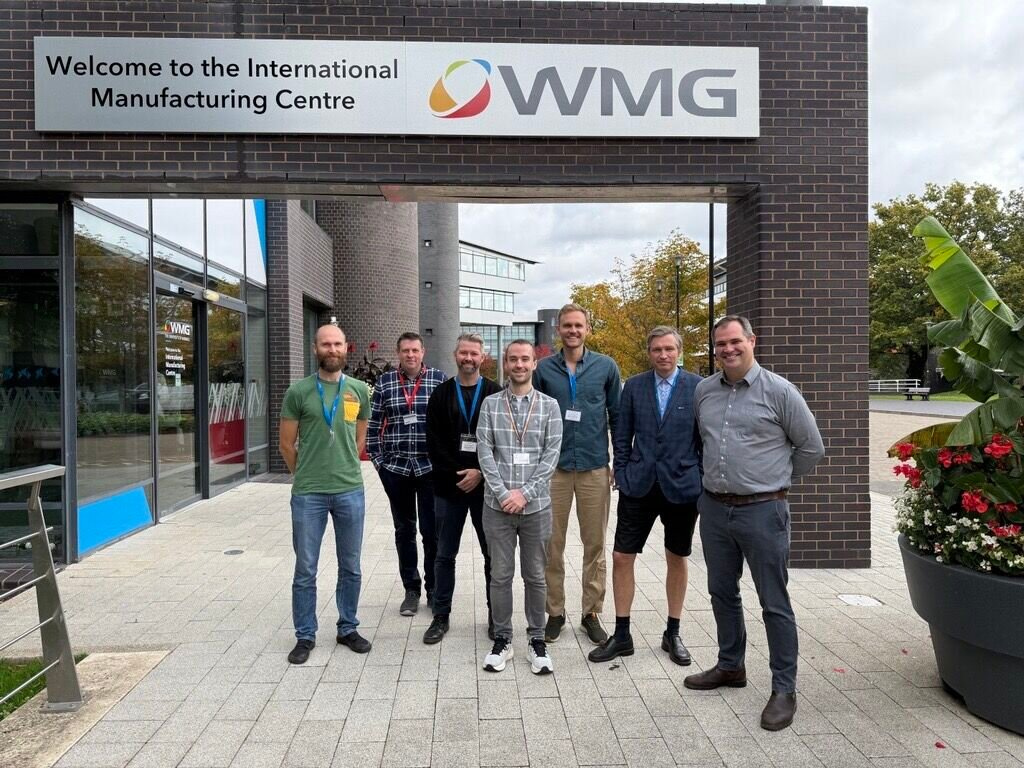 smiling people under a large sign outdoors. photo