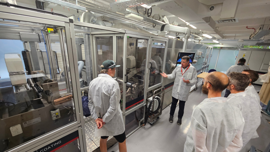 people in white coats next to large lab equipment. photo