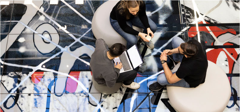 Students sitting on the unique glass floor that forms the artwork Chi Squared by artist Ole Lislerud in the Technology Building at NTNU’s Kalvskinnet campus. Photo: Elin Iversen/NTNU