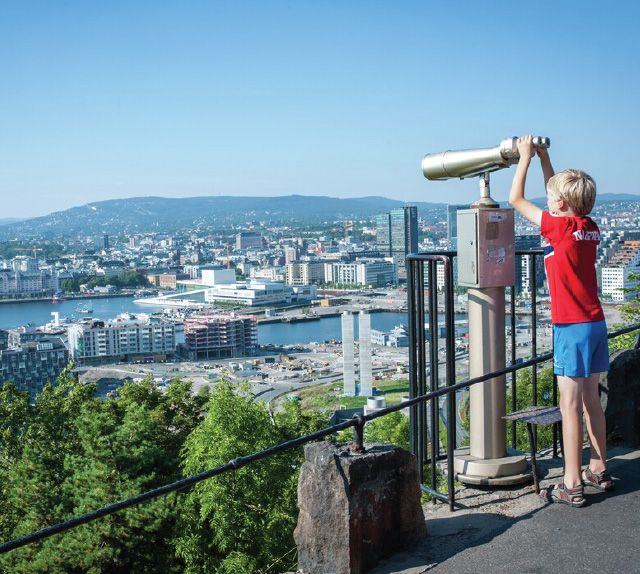 Young boy using public binoculars to view Oslo