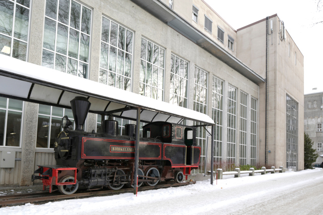 Photo of Kjelhuset building exterior with the steam engine Bjørkelangen in front of the building.