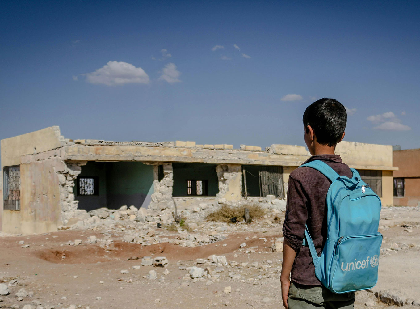 A boy looking at a ruined building. Photo