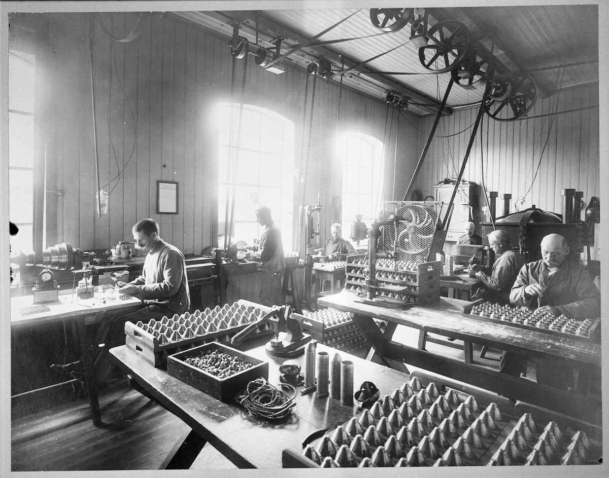 Inside Raufoss Ammunition Factory, six men working, and explosives in front of the picture