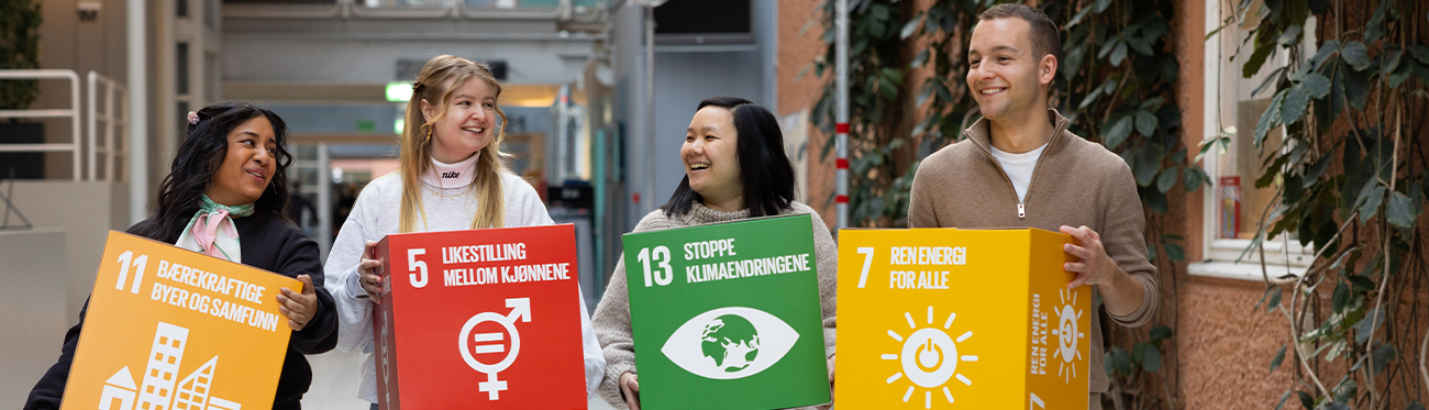 four happy students hold cardboard boxes with different sustainability goals. picture