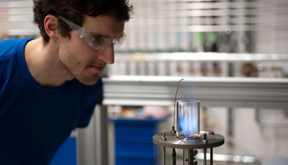 man with lab glasses looking at blue flame. photo