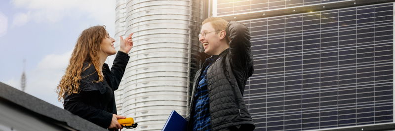 students in front of solar panels on the roof. photo