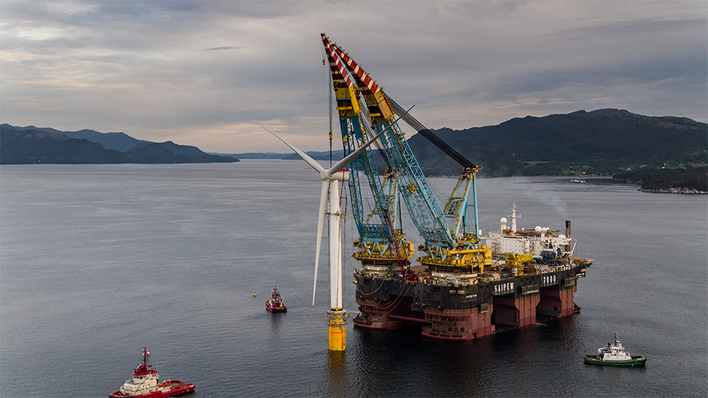 Three boats and a lifting rig around a offshore wind turbine