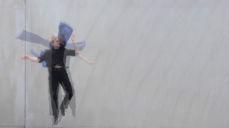 Jumping woman wearing black clothes and a blue scarf