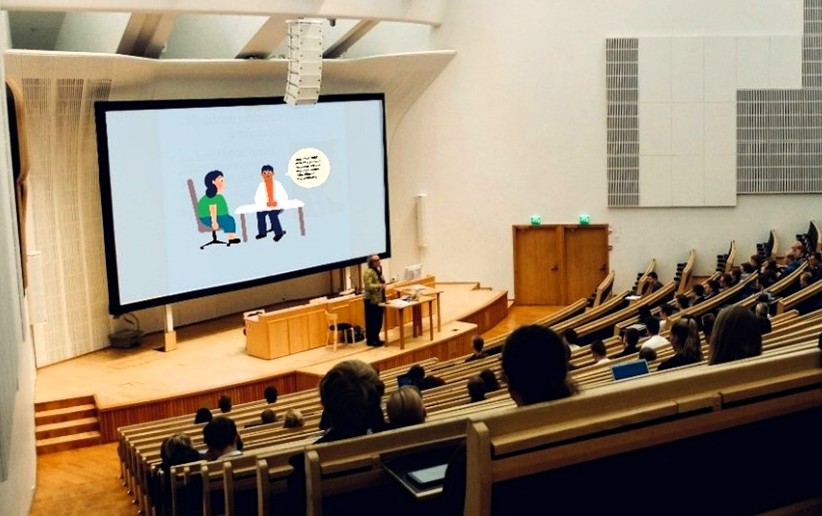Person presenting in a conference hall.