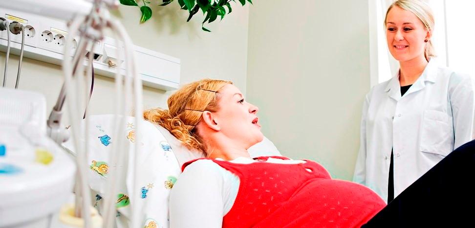 Pregnant woman in hospital bed talking with a woman in hospital clothing