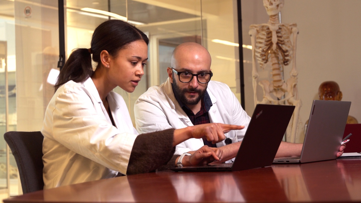 2 students cooperating in front of lap top.
