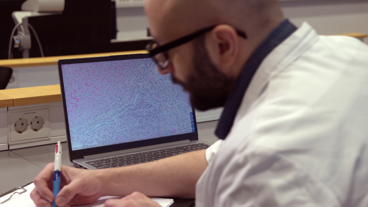 Student taking notes in auditorium.