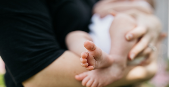 Baby held in parent's arms with the feet exposed to the camera. Pixabay.