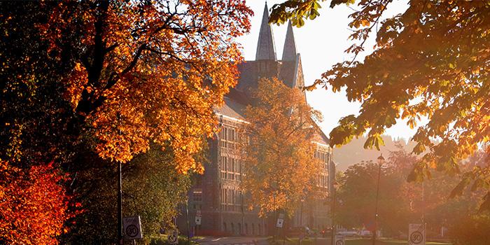 Facade of main building NTNU with autumn coloured trees in the foreground.