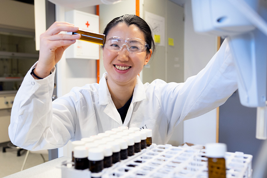 A woman smiling while holding a sample in a laboratory
