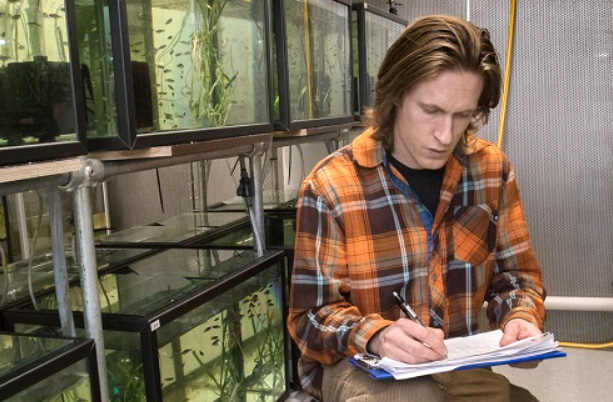 A man taking notes next to aquariums