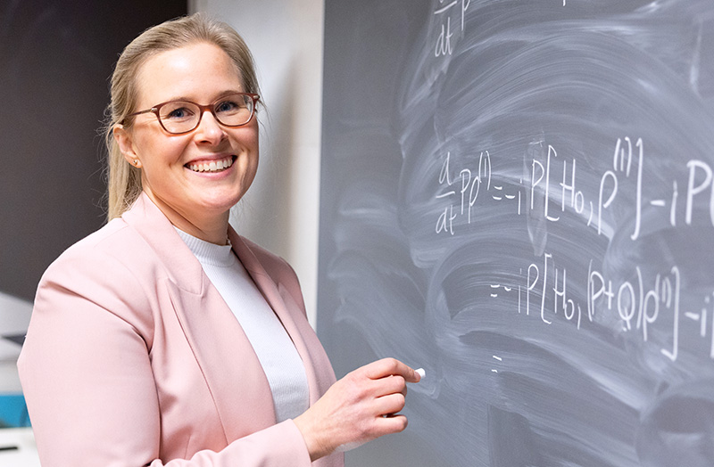 A woman writing on a blackboard smiling