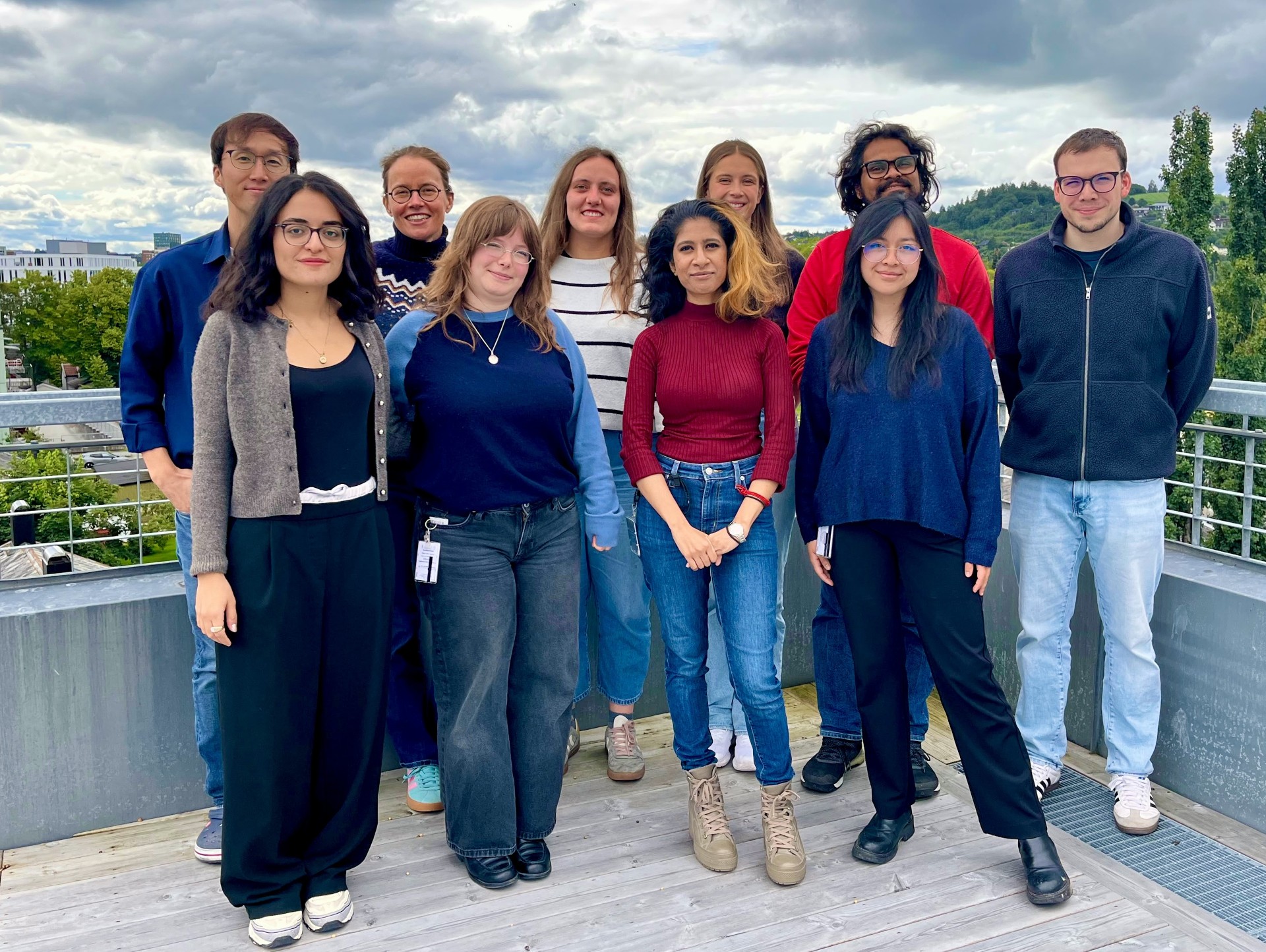 The whole research group of Brain development and physiology. Ten people in total. Outdoor setting with a view of Gløshaugen campus visible in the background.