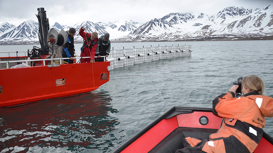 Field work in a boat with snowy mountains in the background. Photo